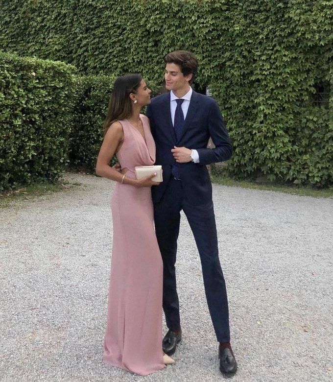 a man in a suit and tie standing next to a woman wearing a pink dress