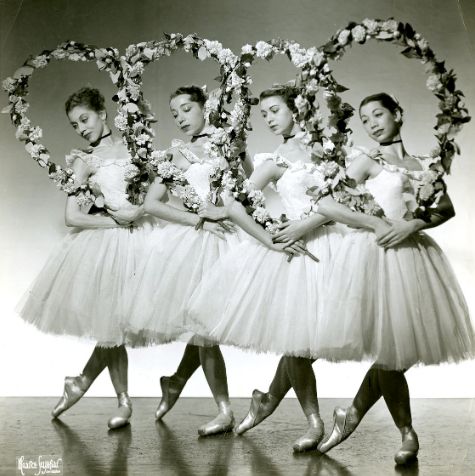 four women in tutu skirts and flower wreaths are posing for the camera with their arms around each other