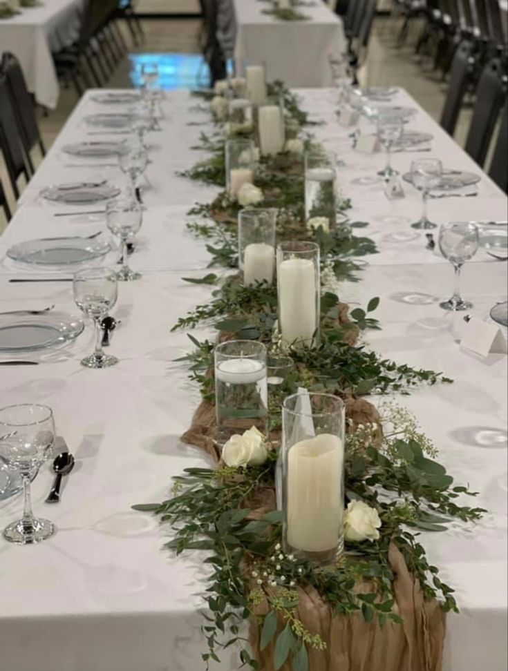 a long table with candles and greenery on it