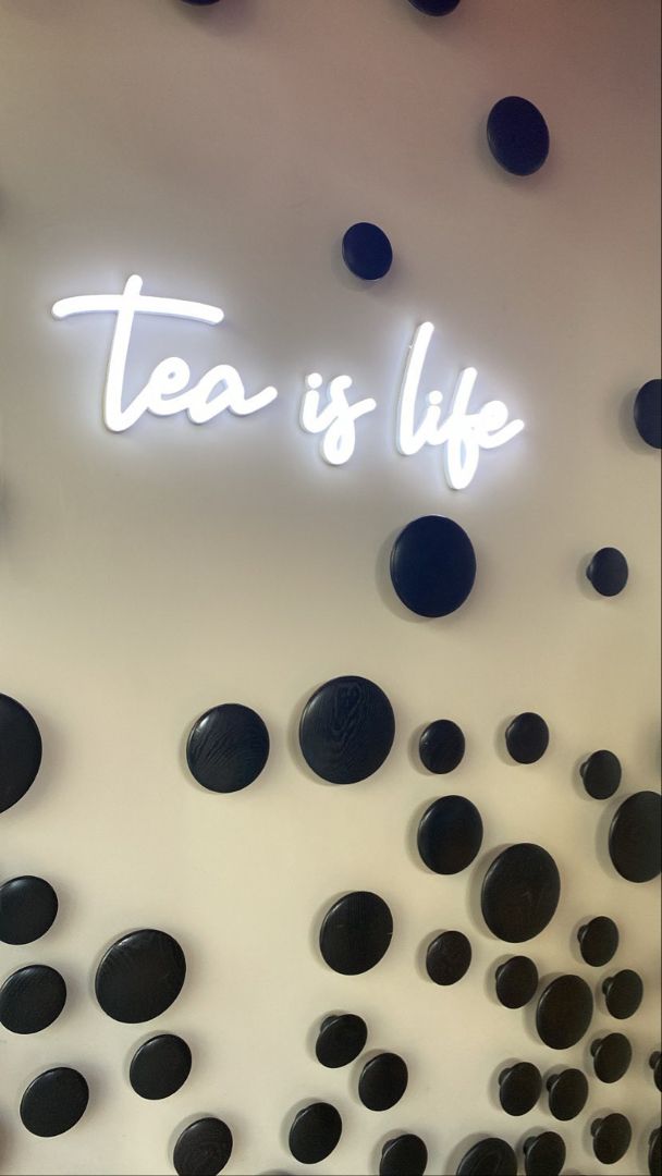 there is a neon sign that says tea is life on the side of a wall