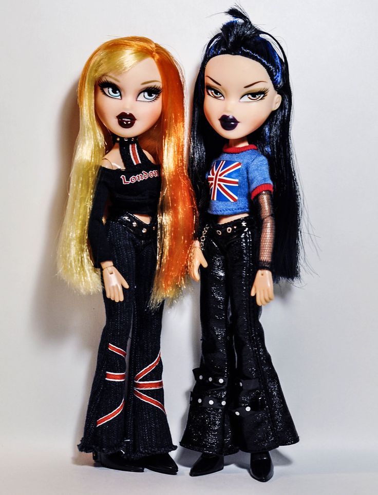 two dolls standing next to each other on a white surface