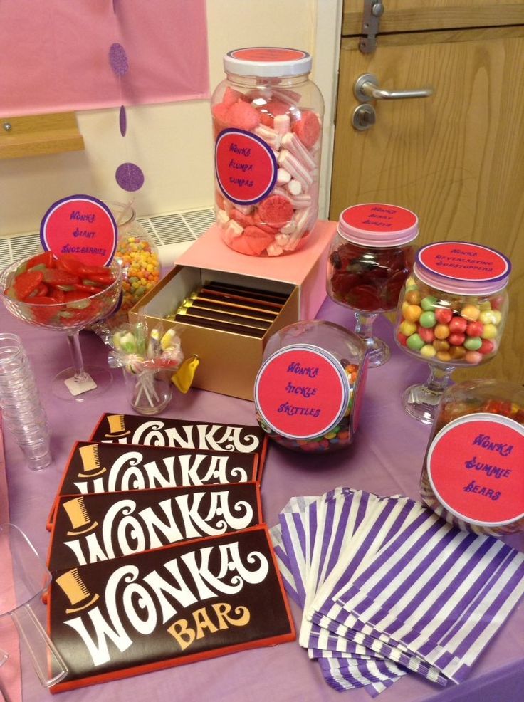 a table topped with candy and candies on top of a purple cloth covered table