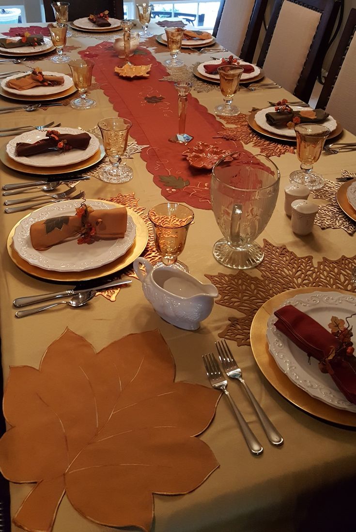 the table is set for thanksgiving dinner with plates and silverware, napkins and place settings