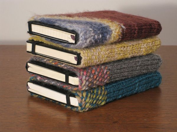 three books are stacked on top of each other, one is covered in multicolored yarn