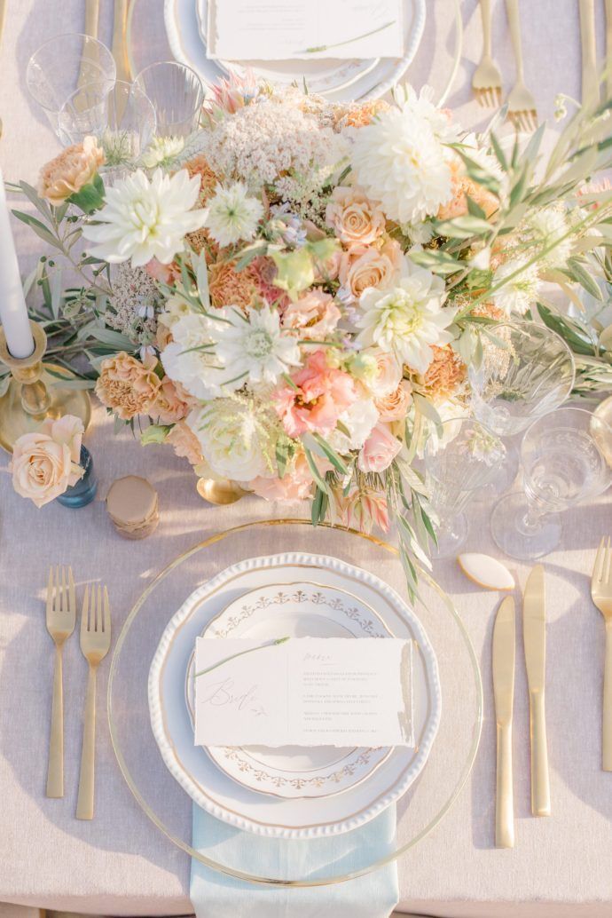 an elegant table setting with white and peach flowers, silverware, and napkins