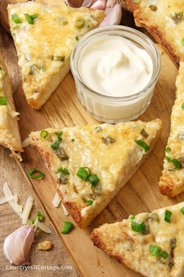 several pieces of pizza sitting on top of a wooden cutting board next to a jar of mayonnaise