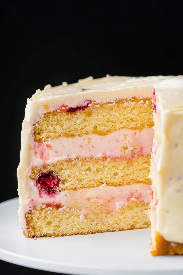 a cake with white frosting and strawberries is cut in half on a plate