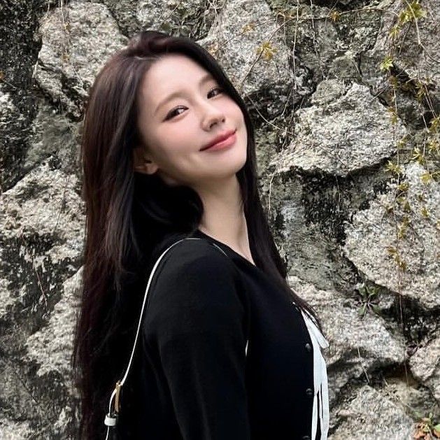 a woman standing in front of a rock wall with her hand on her hip and looking at the camera