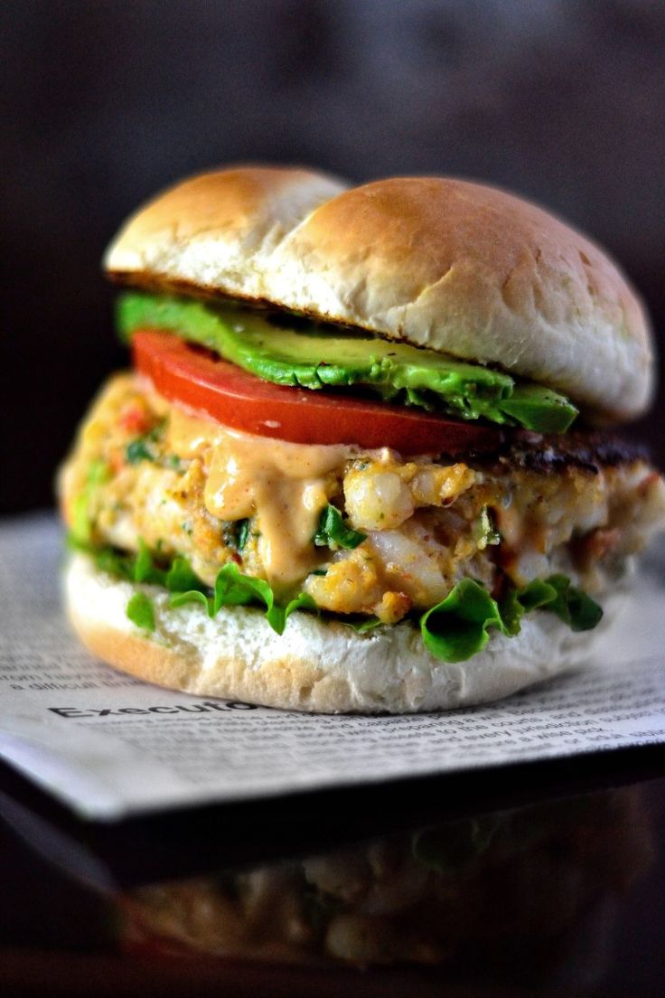 a chicken sandwich with lettuce, tomato and avocado on a white plate