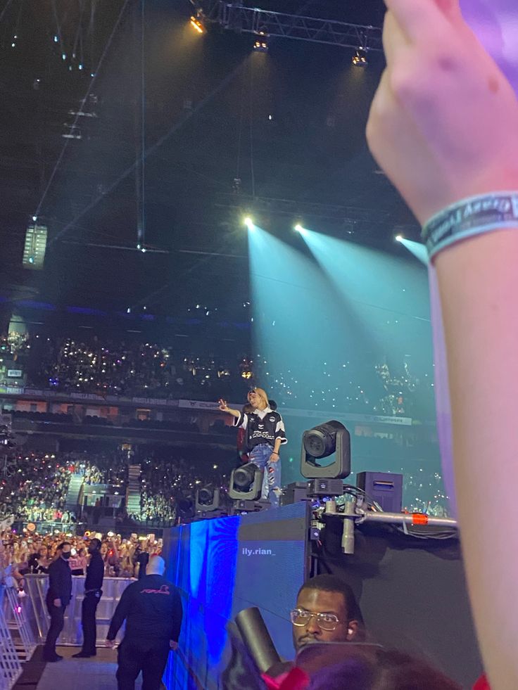 a person standing on top of a stage with their hand up in the air above them