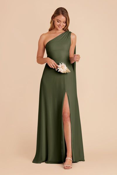 a woman in a green one shoulder dress with high slit and side slit, holding a bouquet