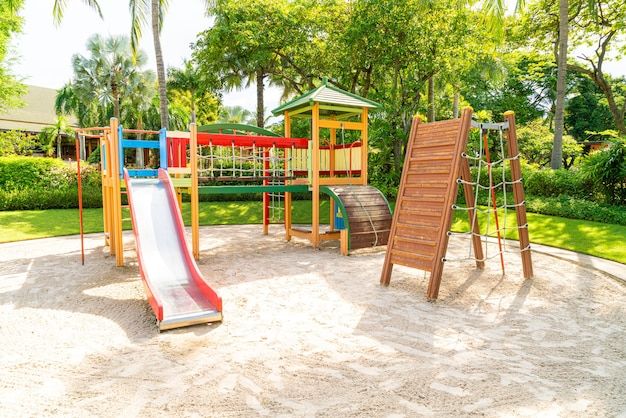 children's play area with swings, slides and climbing frame in park setting on sunny day