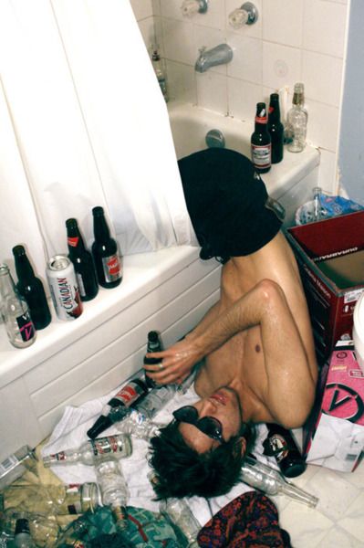 a man sitting on the floor in front of a bathtub full of beer bottles