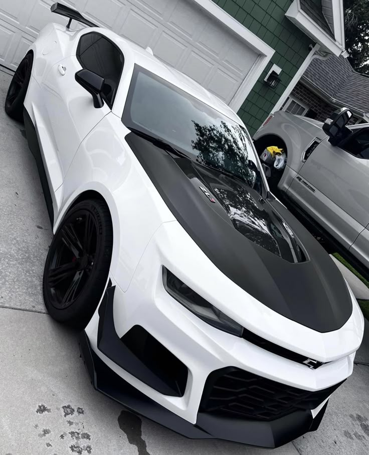 a white sports car parked in front of a garage