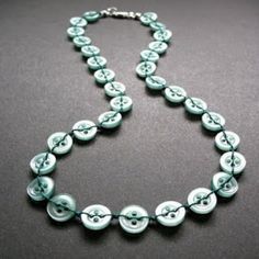 a blue and white necklace with buttons on it's sides, sitting on a black surface