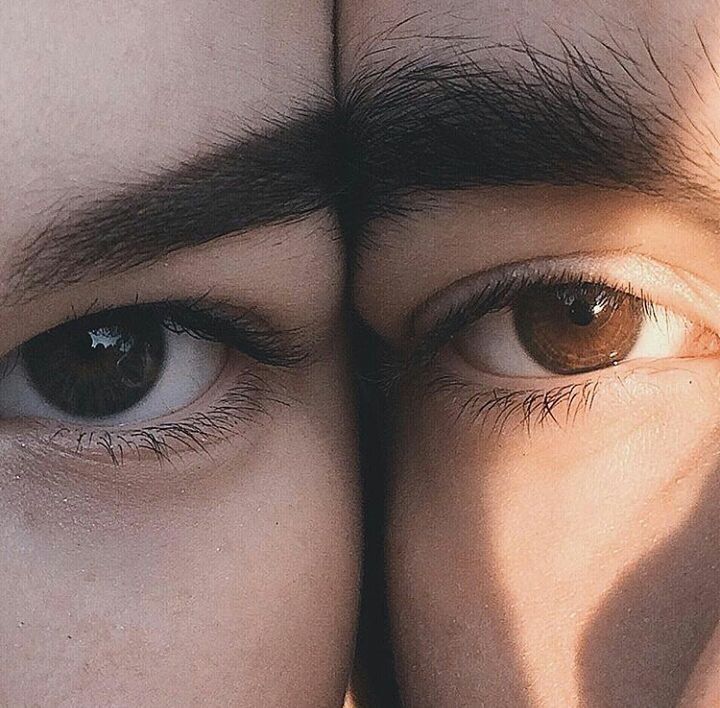 two men with brown eyes are looking at the camera and one is holding his head up