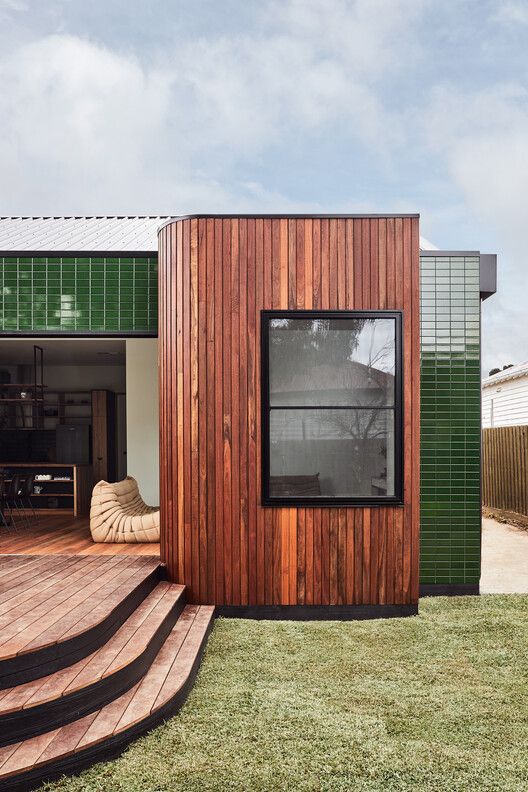 a small wooden building sitting on top of a grass covered field next to a deck