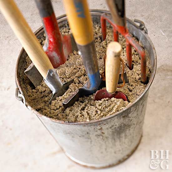 a bucket filled with dirt and gardening utensils