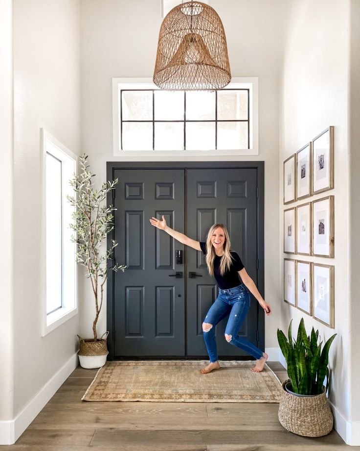 a woman standing in front of a black door with her arms outstretched and legs crossed