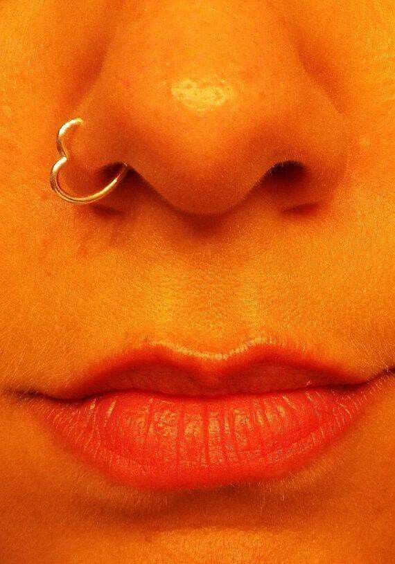 a woman's nose with an open nose ring attached to her lip and the bottom part of her nose