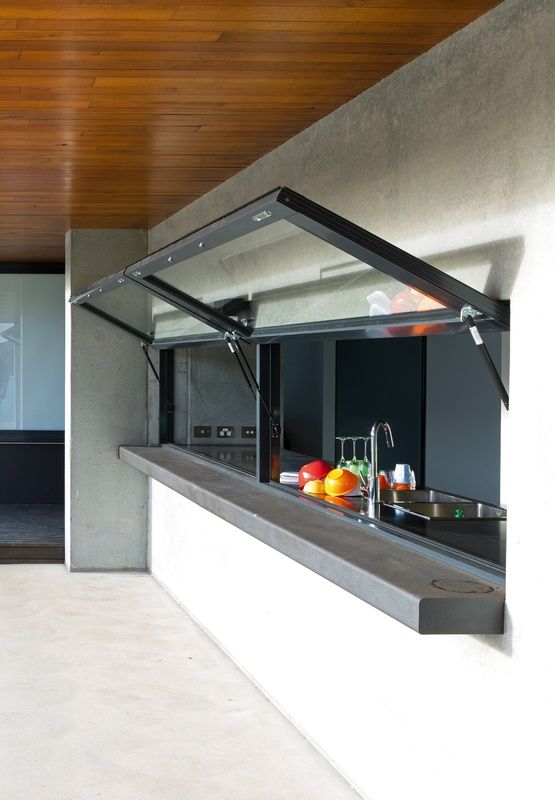 an open kitchen and living room area in a modern house with wood ceilinging, concrete walls