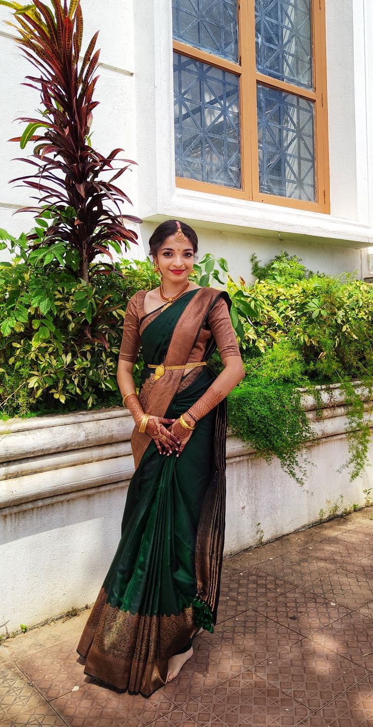 a woman in a green and brown sari posing for the camera with her hands on her hips