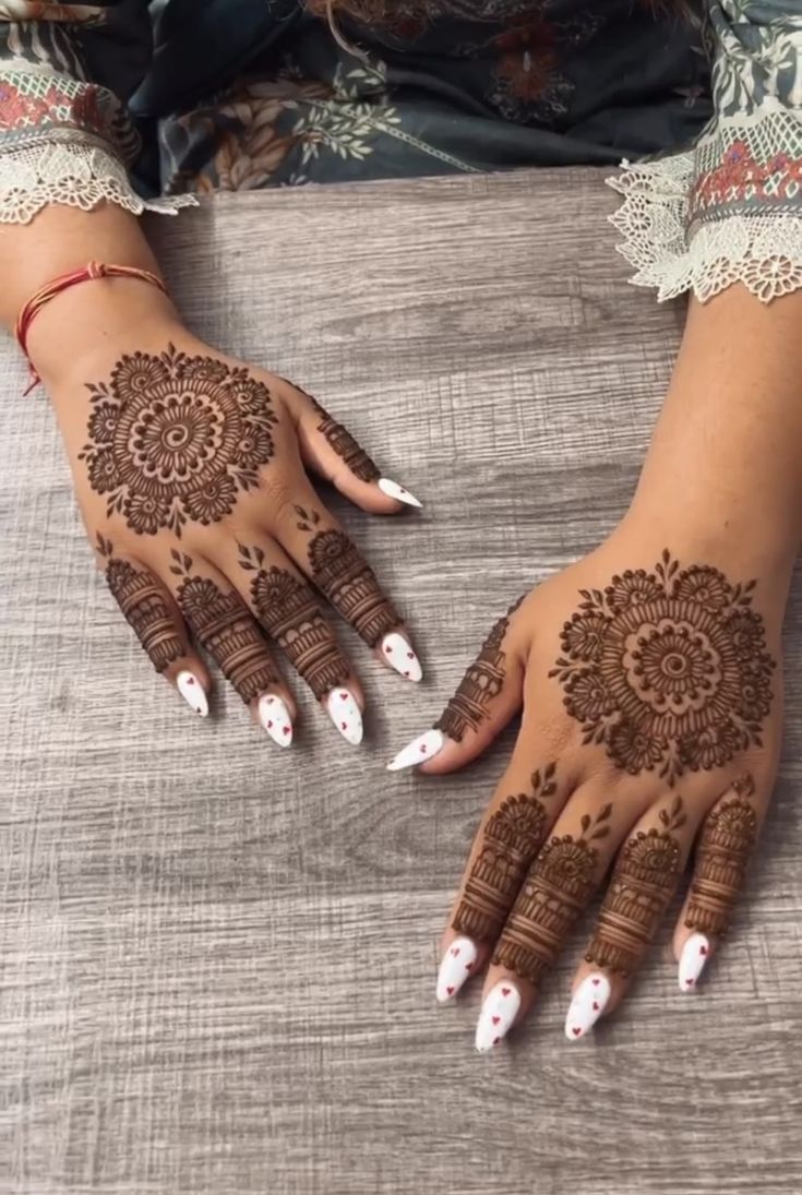 two hands with henna designs on them, one is white and the other is brown