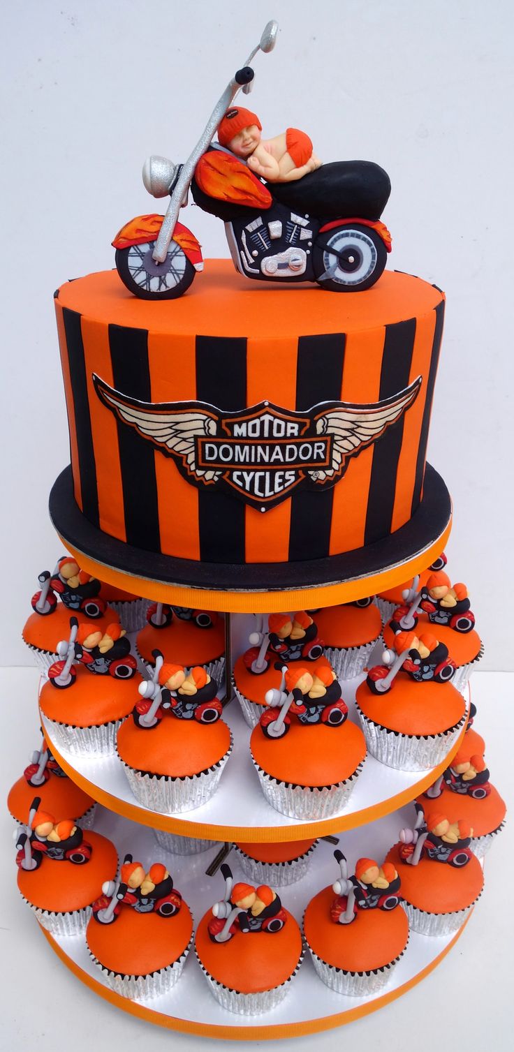 an orange and black motorcycle themed cake with cupcakes