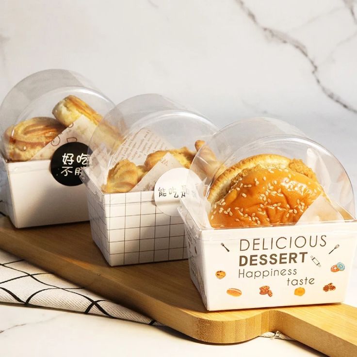 three plastic containers filled with pastries on top of a wooden tray