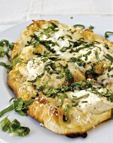 a white plate topped with pizza covered in cheese and greens