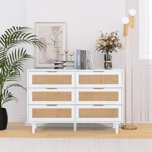 a white dresser with wicker drawers next to a potted plant