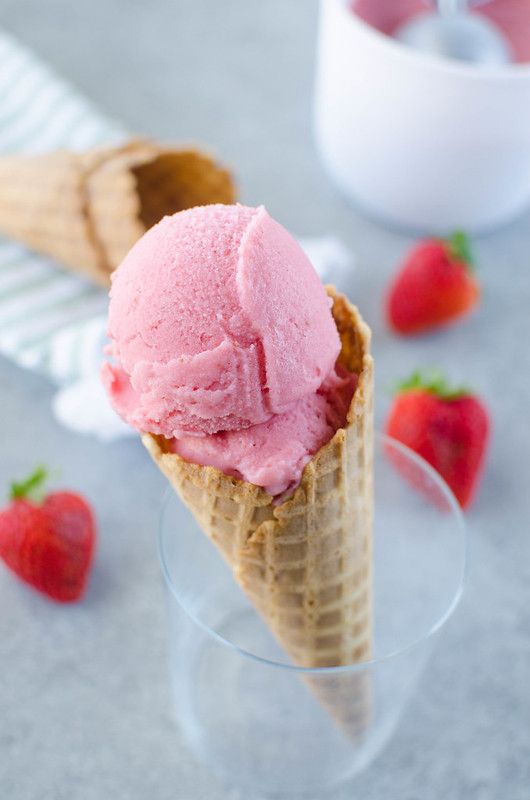 two scoops of ice cream with strawberries on the side