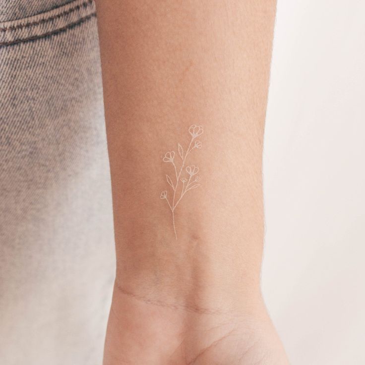 a small white flower tattoo on the wrist