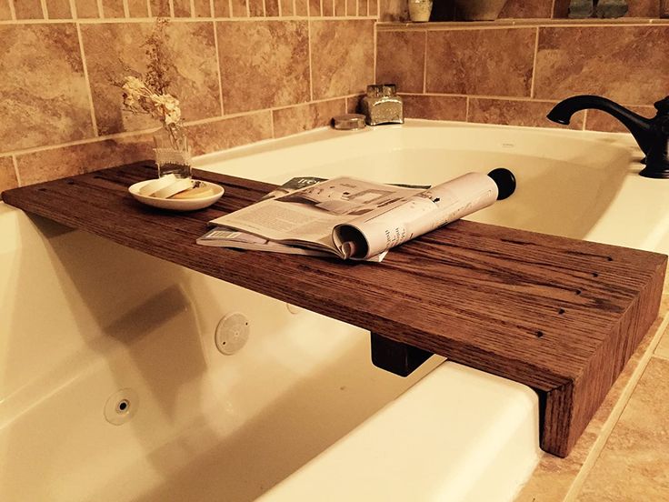 a bath tub with a wooden shelf in the middle and a newspaper on it's edge