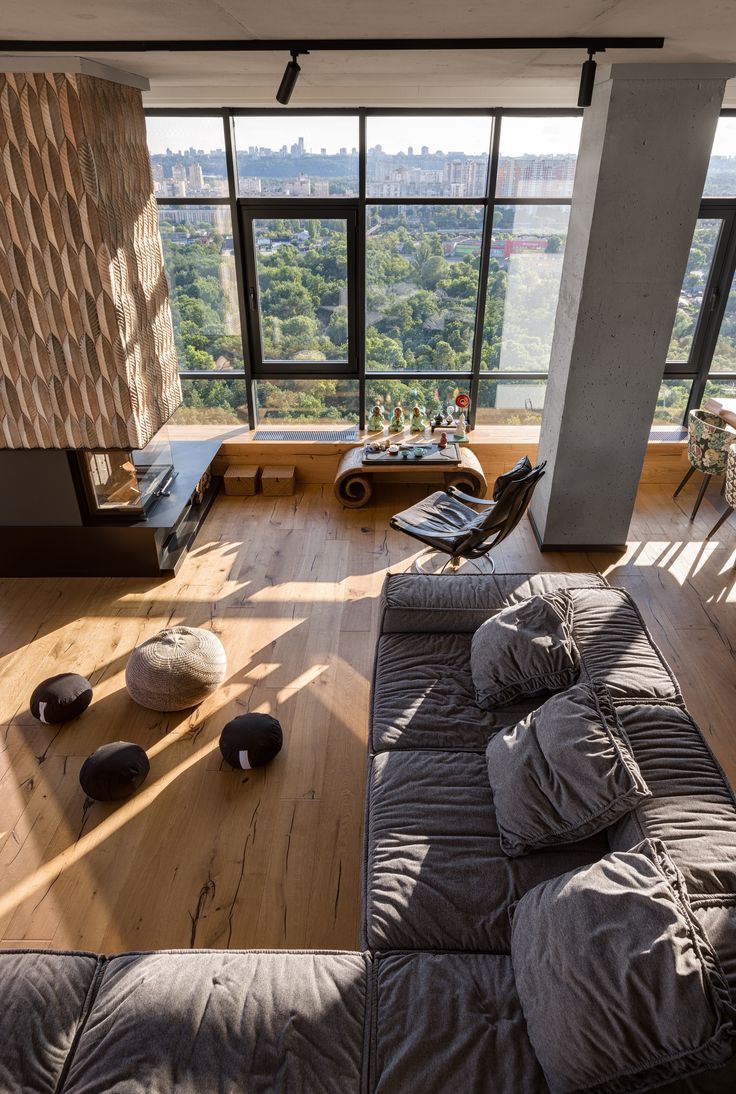 a living room filled with lots of furniture and large windows overlooking the surrounding cityscape