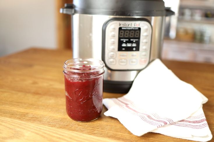 a jar of red liquid sitting next to an instant pot with the lid on it