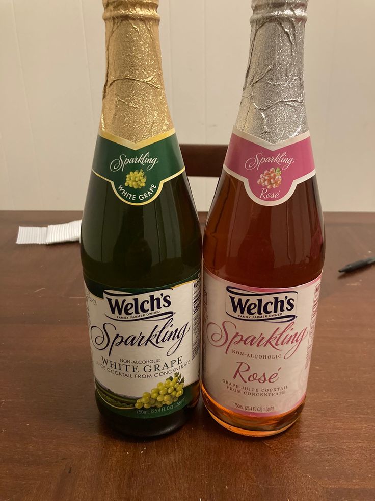 two bottles of sparkling wine sitting on top of a wooden table next to each other