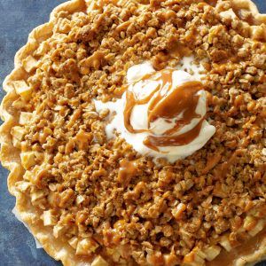 a pie topped with whipped cream and pecans on a blue tablecloth next to a fork