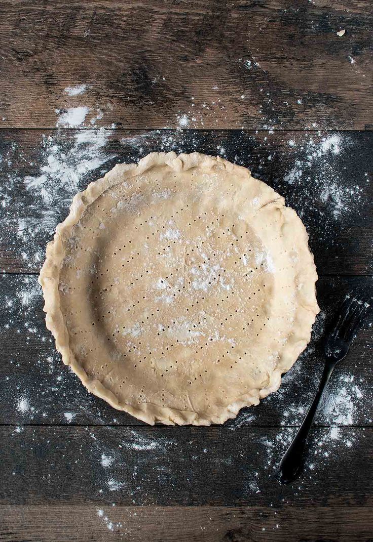 an uncooked pie crust sitting on top of a wooden table next to a knife