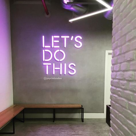 a purple neon sign that says let's do this on the wall next to a bench