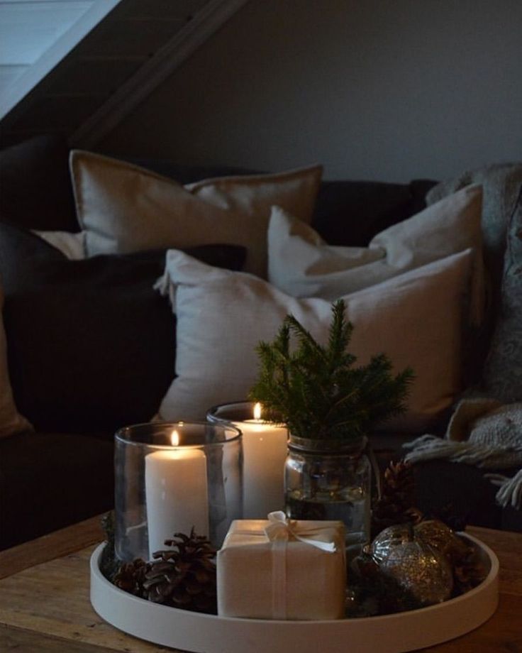 some candles are sitting on a tray with pine cones