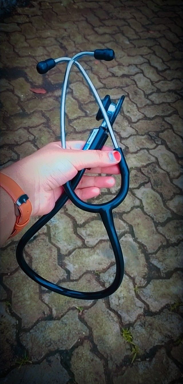 a person holding a stethoscope in their hand on the ground with cobblestone