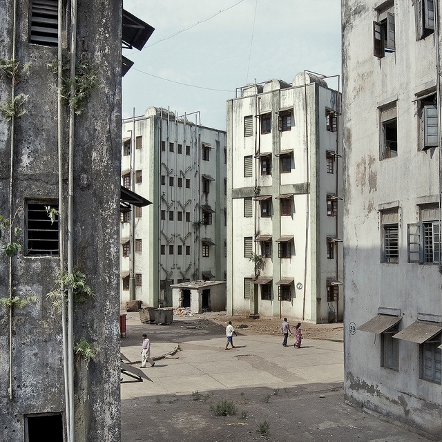 an alley way between two buildings with children playing in the courtyard and on the other side