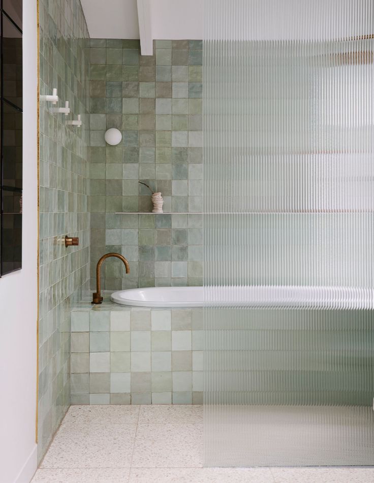 a white bath tub sitting next to a tiled wall