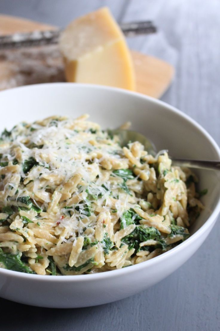 a white bowl filled with pasta and spinach