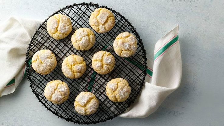 several powdered sugar cookies sitting on a cooling rack next to a cloth and napkin