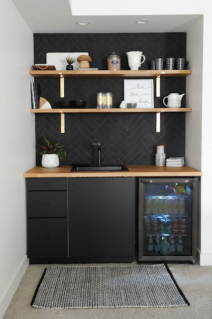 a kitchen area with shelves, cabinets and a rug on the floor in front of it