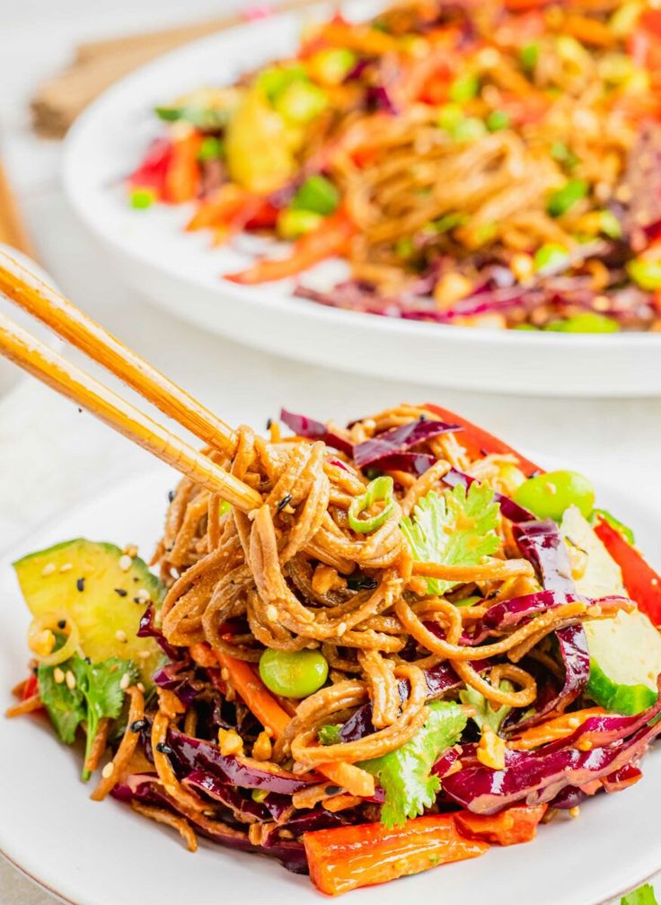 two white plates filled with food and chopsticks