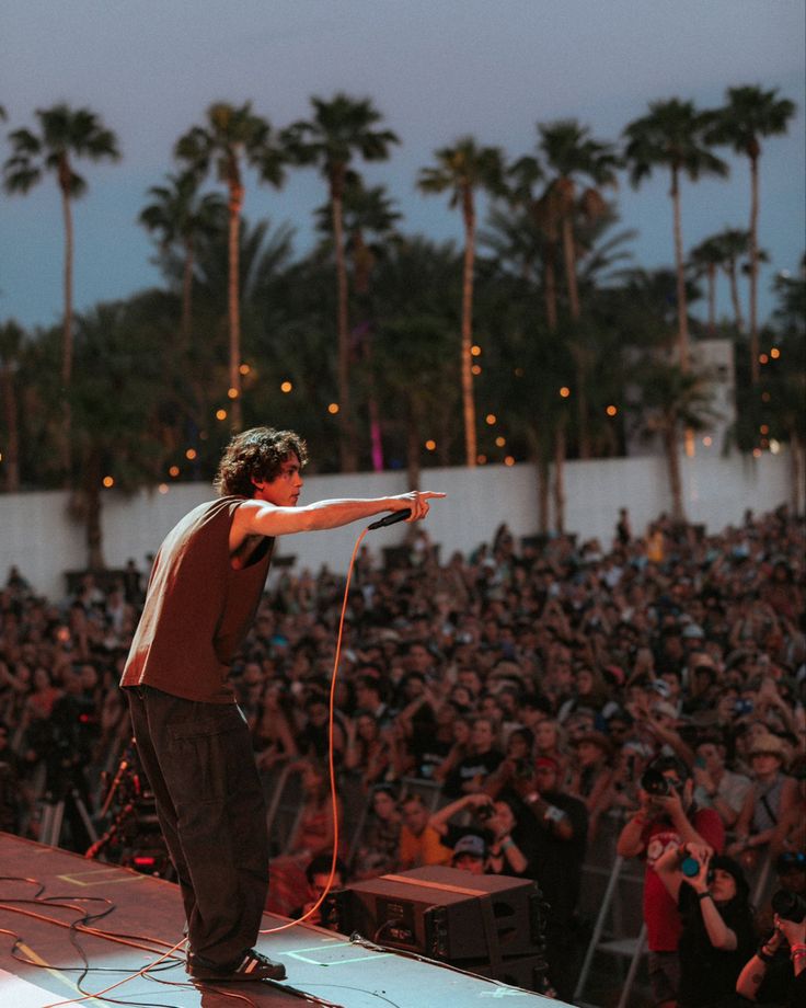 a man standing on top of a stage holding a microphone in front of a crowd