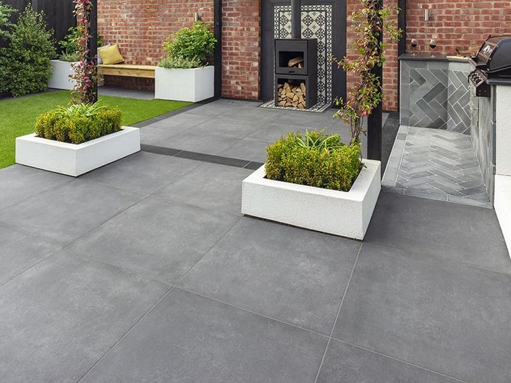 an outdoor living area with potted plants and grill